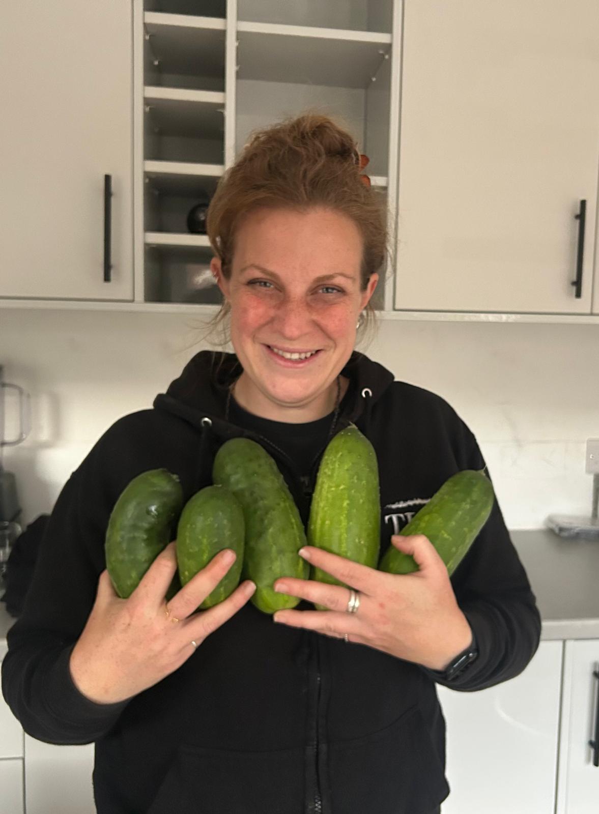 Gabriela harvesting fresh cucumbers in the garden
